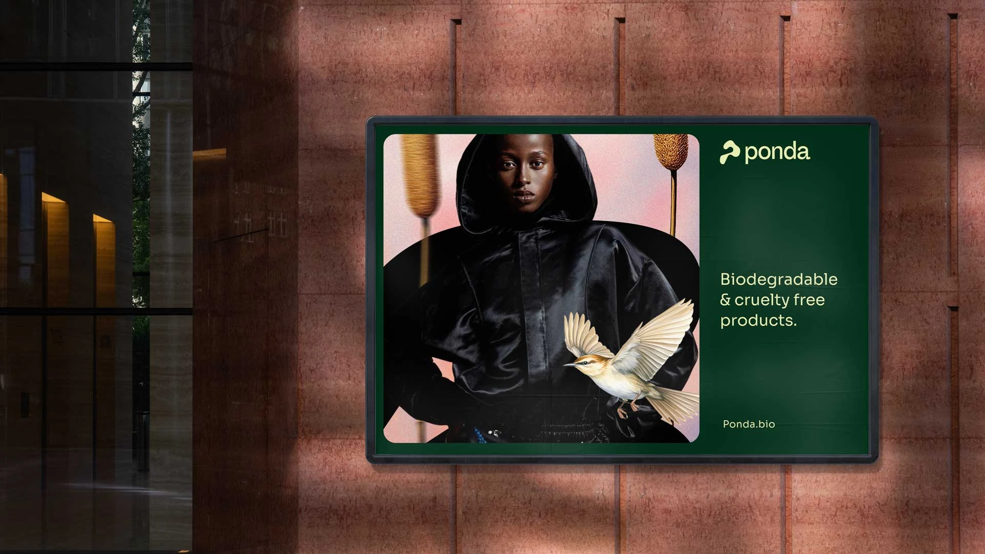 Billboard ad with model in black hooded jacket, bird, and text promoting biodegradable cruelty-free products using biopuff technology