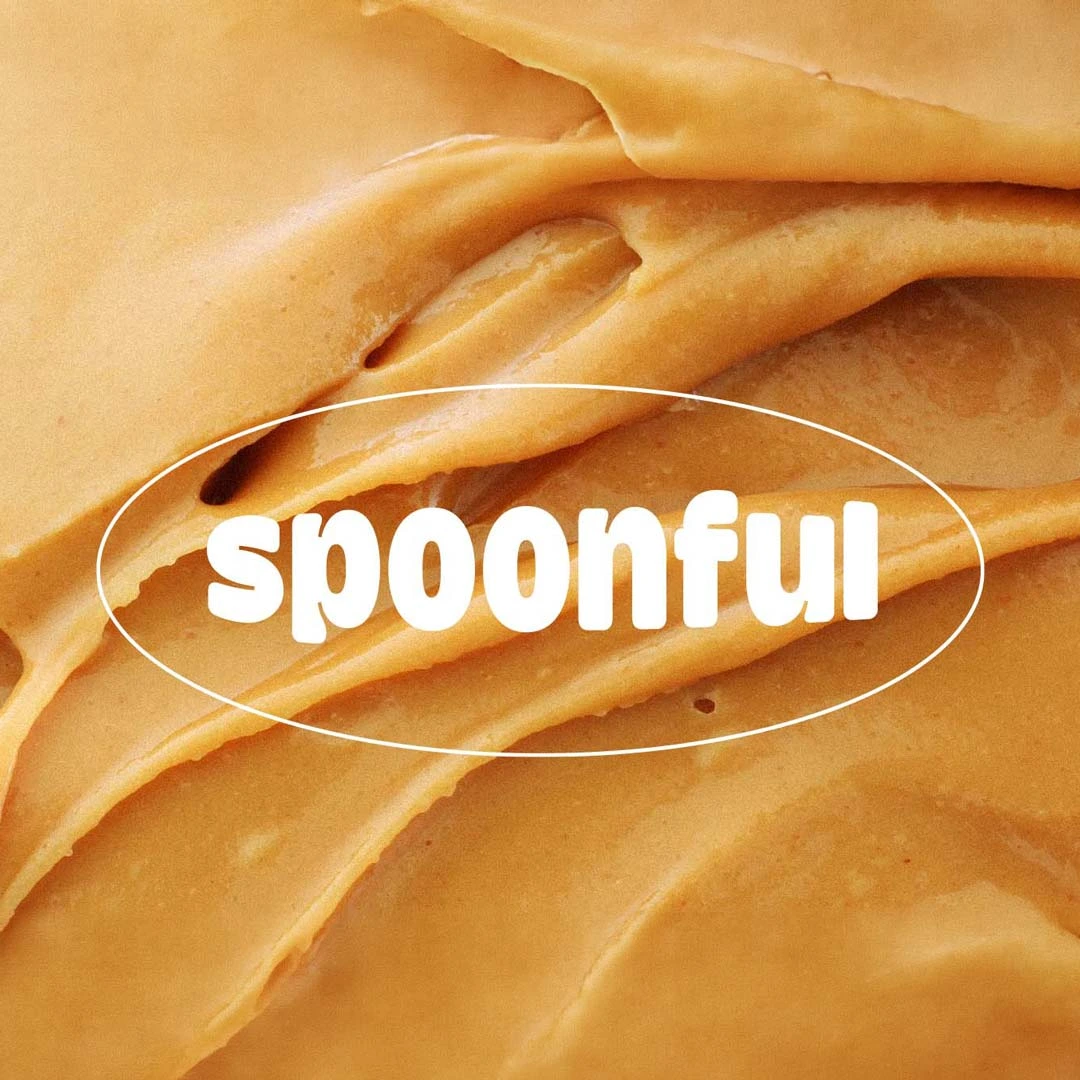Close-up of creamy peanut butter with the word spoonful in white text overlayed.